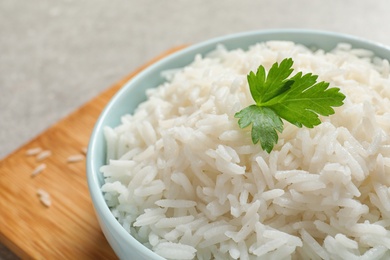 Bowl of delicious rice with parsley on table, closeup