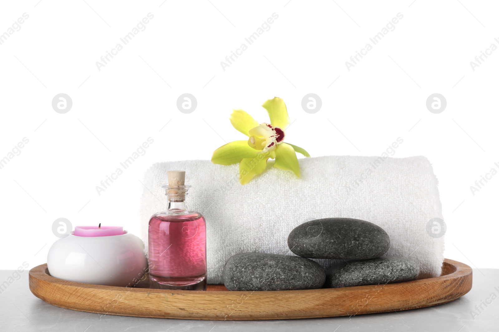 Photo of Tray with towel and spa supplies on grey table against white background