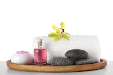 Tray with towel and spa supplies on grey table against white background