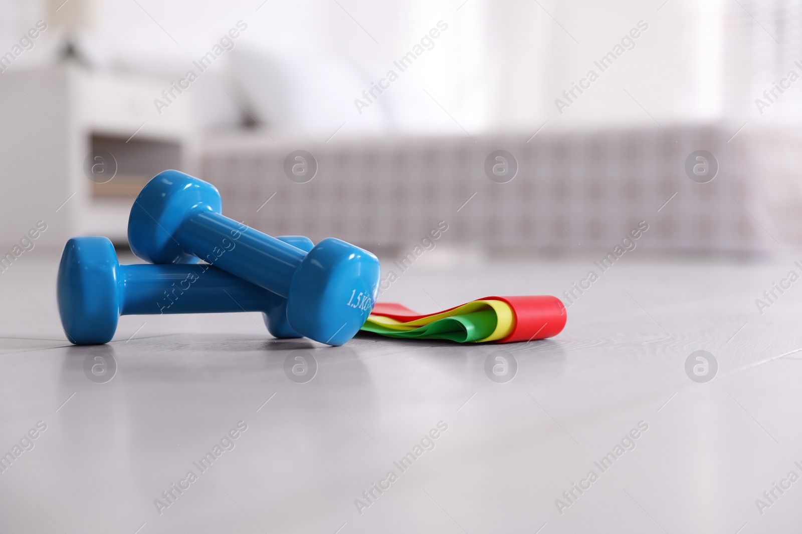 Photo of Dumbbells and different elastic bands on floor in room. Home fitness