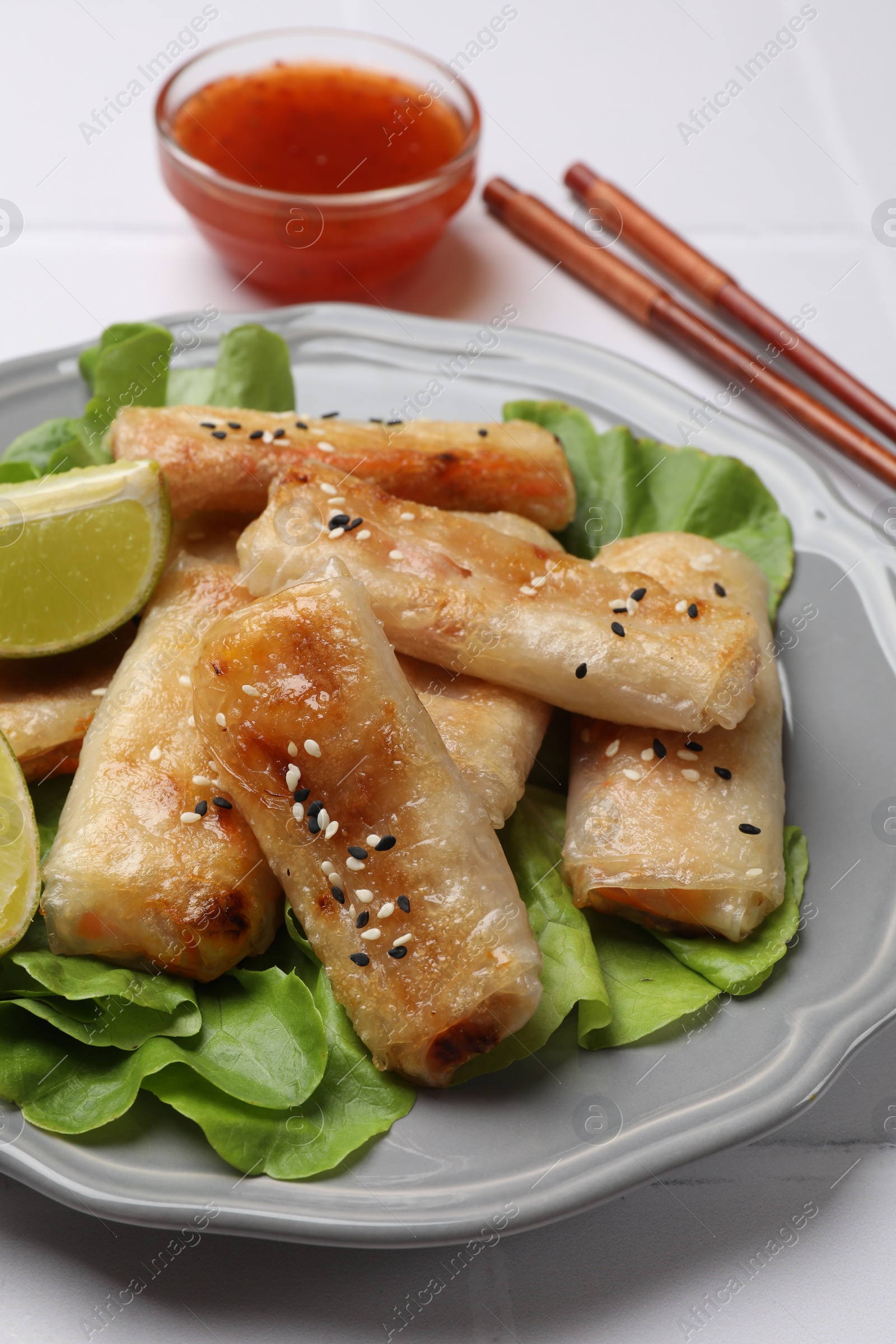 Photo of Tasty fried spring rolls served on light table, closeup