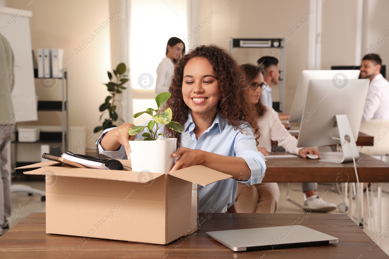 Photo of New coworker unpacking box with personal items at workplace in office