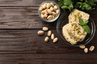 Photo of Tasty halva with pistachios and mint on wooden table, flat lay. Space for text