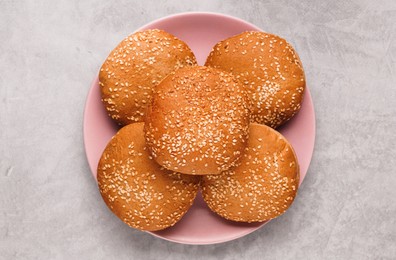 Photo of Fresh buns with sesame seeds on light grey table, top view