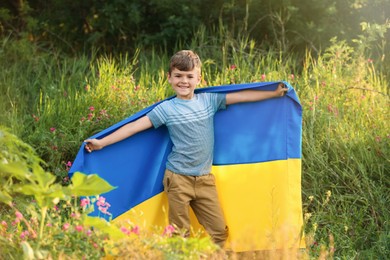 Photo of Little boy with national flag of Ukraine in field