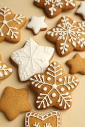 Photo of Tasty Christmas cookies with icing on beige background, closeup