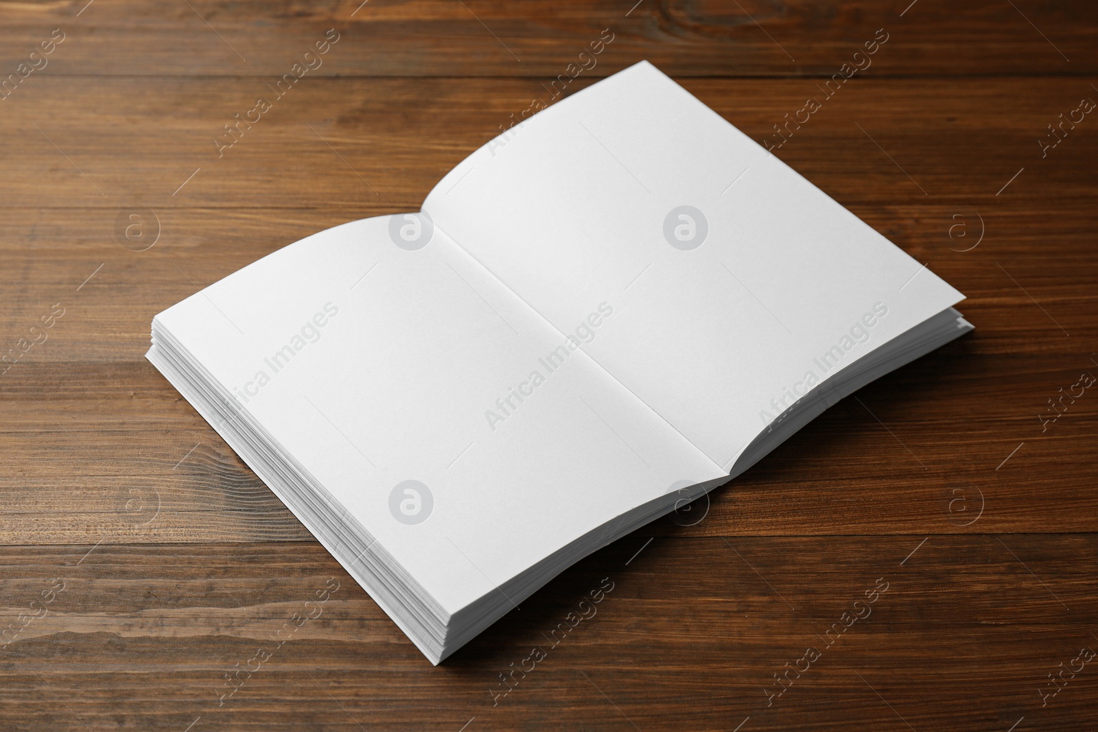 Photo of Open blank paper brochure on wooden table. Mockup for design