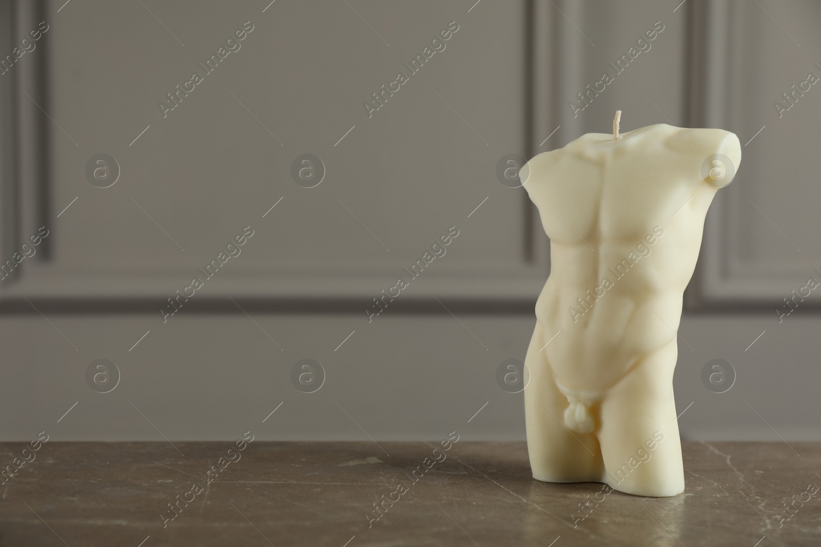 Photo of Beautiful male body shape candle on grey table. Space for text