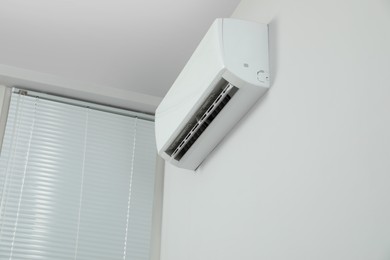 Photo of Modern air conditioner on white wall indoors, low angle view. Space for text