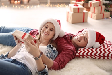 Photo of Young couple with Christmas gift at home