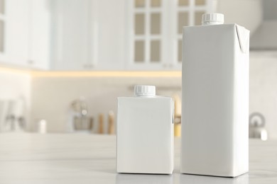 Photo of Carton boxes of milk on table in kitchen, space for text