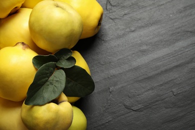 Photo of Fresh ripe organic quinces with leaves on black table, closeup. Space for text