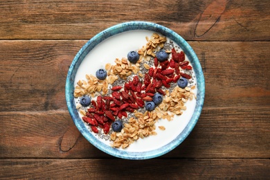 Photo of Smoothie bowl with goji berries on wooden table, top view