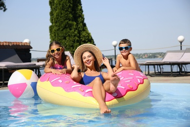 Photo of Woman with her children in swimming pool. Family vacation