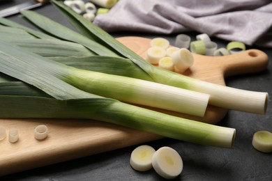 Photo of Fresh raw leeks on black table, closeup