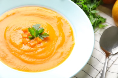 Photo of Plate with tasty pumpkin soup on table, closeup view