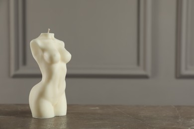 Beautiful female body shape candle on grey table. Space for text