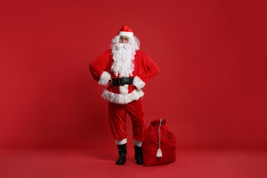Photo of Santa Claus and bag of Christmas presents on red background