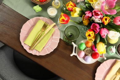 Festive Easter table setting with beautiful flowers and painted eggs, top view
