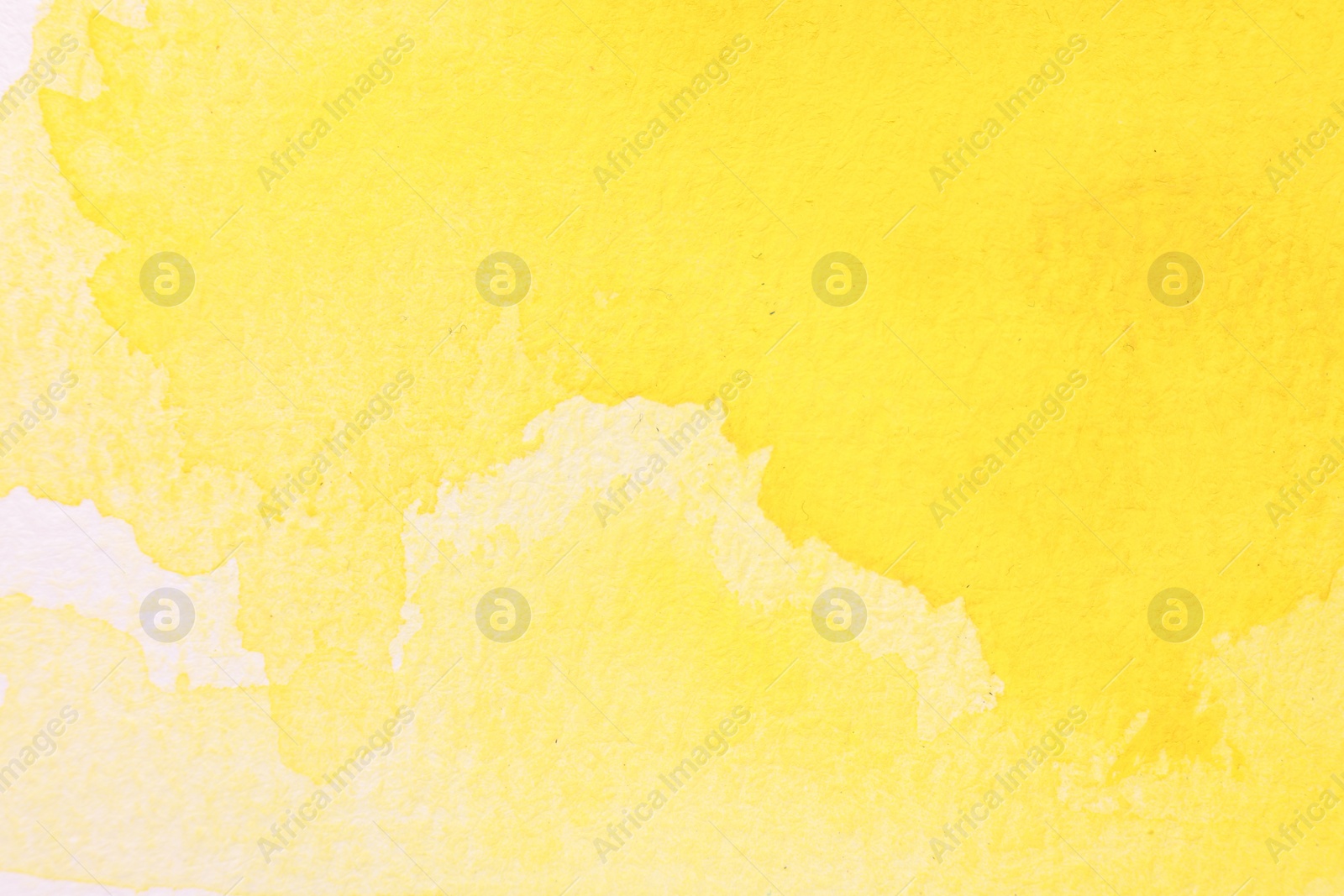 Photo of Abstract yellow watercolor painting on white paper, top view