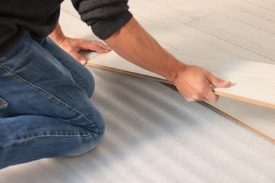Photo of Professional worker installing new laminate flooring, closeup