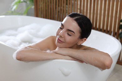 Photo of Beautiful young woman taking bubble bath at home
