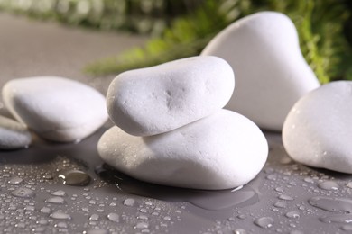 Photo of White spa stones with water drops on grey background, closeup