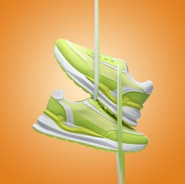Image of Pair of stylish sneakers in air on orange background