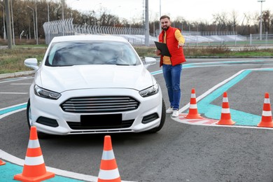 Photo of Instructor near car with his student during exam at driving school test track