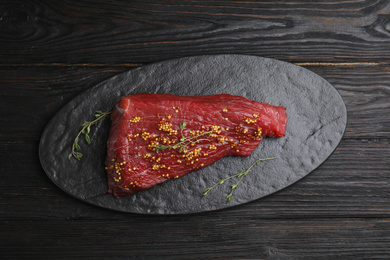 Photo of Fresh raw beef cut with thyme and mustard on wooden table, top view
