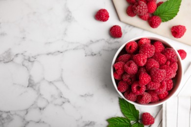 Photo of Bowl with fresh ripe raspberries on white marble table, flat lay. Space for text