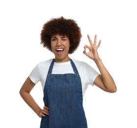 Photo of Happy young woman in apron showing ok gesture on white background