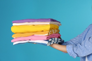 Photo of Young woman holding clean laundry on color background, closeup