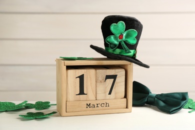 Composition with leprechaun hat and block calendar on white wooden table. St Patrick's Day celebration