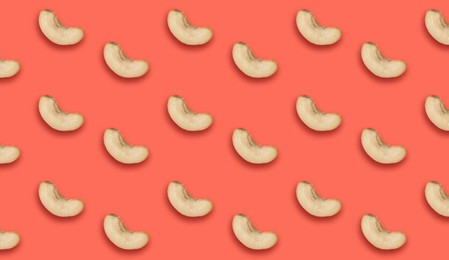 Image of Many tasty cashew nuts on coral background, flat lay. Banner design