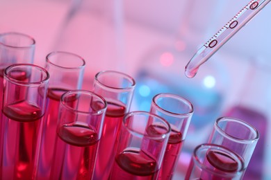 Photo of Dripping reagent into test tube with red liquid, closeup. Laboratory analysis