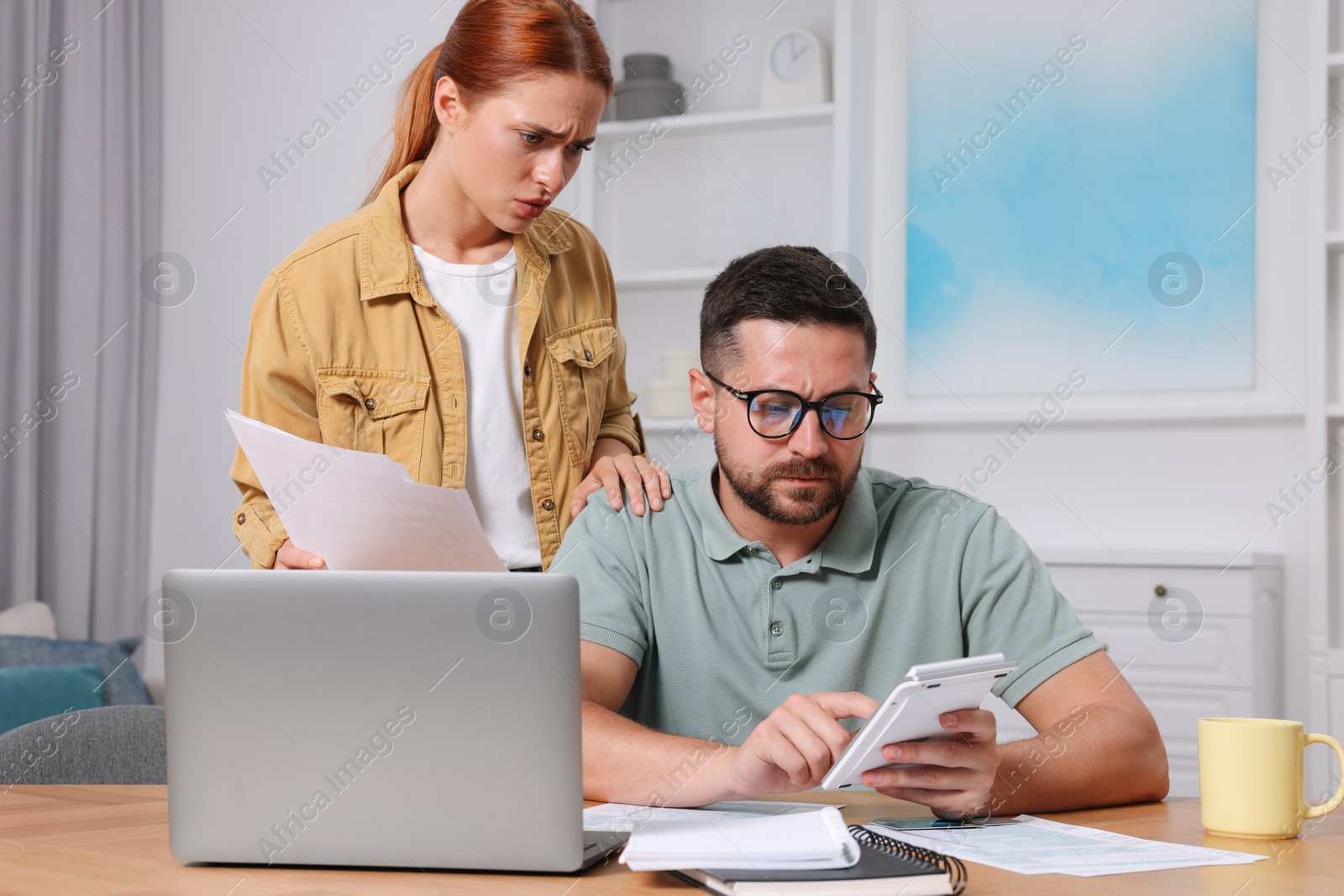 Photo of Couple calculating taxes for online payment at table in room