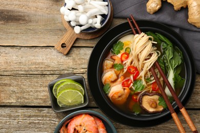 Photo of Flat lay composition with delicious ramen in bowl and ingredients on wooden table, space for text. Noodle soup