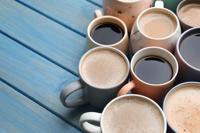 Many cups of different coffee drinks on light blue wooden table