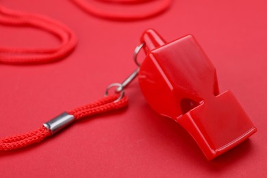Photo of One color whistle with cord on red background, closeup