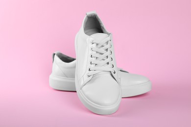 Photo of Pair of stylish white sneakers on pink background