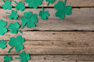 Photo of St. Patrick's day. Decorative clover leaves on wooden background, flat lay. Space for text