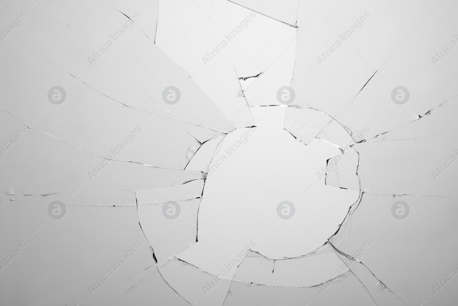 Photo of Closeup view of broken glass with cracks on white background