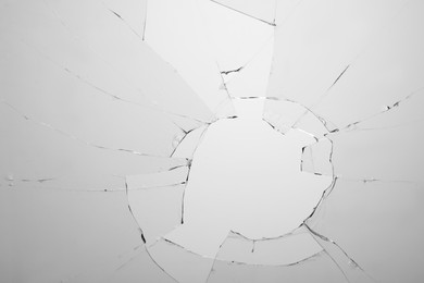 Photo of Closeup view of broken glass with cracks on white background