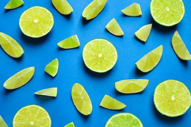 Photo of Juicy fresh lime slices on blue background, flat lay