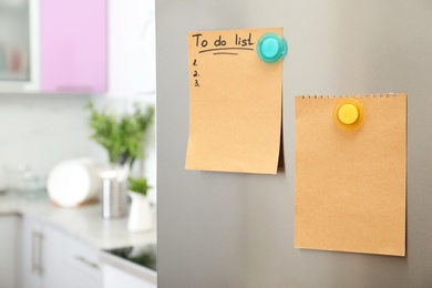 Photo of To do list and empty sheet of paper with magnets on refrigerator door in kitchen. Space for text