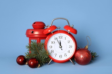 Photo of Alarm clock and festive decor on blue background. New Year countdown
