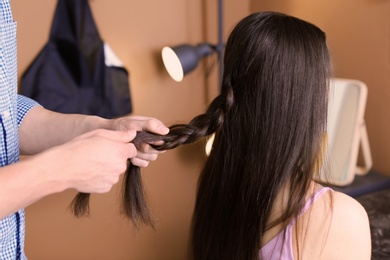Photo of Professional hairdresser working with client in beauty salon
