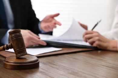 Photo of Senior woman signing document in lawyer's office, focus on gavel