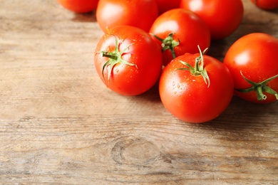 Photo of Fresh ripe tomatoes on wooden table, closeup. Space for text